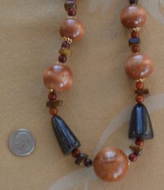 "Featuring this very attractiveshades of brown beaded necklace that is a mix of wooden, stone and horn beads. The wooden beads have gold tone filigree cap accents. The necklace measures 26\" in length and has a spring ring clasp. The necklace is in very good vintage condition." Unique Brown Beaded Necklace With Polished Beads, Unique Brown Polished Beads, Adjustable Brown Wooden Necklaces, Earthy Polished Brown Beads, Artisan Brown Hand-strung Beaded Necklaces, Earthy Brown Polished Beads, Earthy Hand-strung Brown Beaded Necklaces, Brown Wooden Beaded Jewelry, Earthy Brown Hand-strung Beaded Necklaces