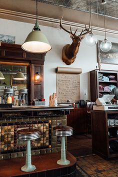 a bar with two stools and a deer head mounted on the wall above it