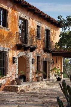 an old building with many windows and balconies on the outside, surrounded by cactuses