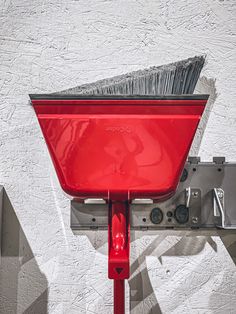 a red wheelbarrow is attached to a white wall