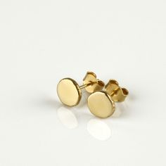 "Shiny round gold 14k stud earrings, simple and perfect for every day's wear. These gold earrings are handmade of yellow 14k solid gold. I melted the gold into a ball, and then hammered each ball to its irregular shape. No two are ever identical, and each has a unique and organic look. The edges of the pebbles are rough, while the flat surface has a smooth shiny finish. These are classic \"wear with everything\" gold earrings - a perfect gift, or a treat for you. Earrings diameter is approx 7 mm Minimalist 14k Gold Round Cut Earrings, Classic Yellow Round Earrings, Gold 14k Gold-filled Round Earrings, 14k Gold-filled Round Earrings, Yellow Minimalist Round Earrings, Gold Minimalist Earrings, Simple Studs, Classic Wear, Minimalist Earrings Gold