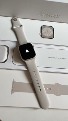 an apple watch sitting on top of a white box next to another device with its lid open