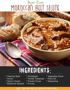 a bowl of beef stew on top of a table next to bread and spoons