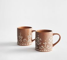 two brown mugs with snowflakes on them are sitting side by side in front of a white background