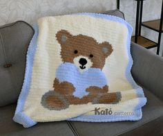 a crocheted teddy bear blanket sitting on top of a couch