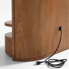 an electric cord is plugged into the side of a wooden cabinet with two shelves