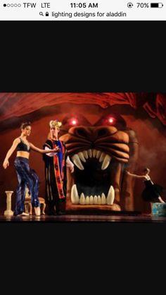 two people are standing on stage with an evil monster in the background and one person is holding