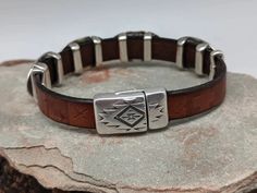 The Southwest Sunburst bracelet has 4 Southwest sliders that are on embossed leather with a Southwestern pattern. Magnetic clasp with an easy open thumbnail slot that stays put. The components are zinc plated with 99.9% sterling silver. Free of nickel, lead, cadmium. Hypoallergenic. The leather is 10mm in width. One size fits most. 8" Southwestern Style Brown Concho Bracelets, Southwestern Adjustable Nickel Free Bracelets, Adjustable Southwestern Jewelry With Sterling Silver Clasp, Rustic Adjustable Etched Jewelry, Adjustable Southwestern Hand-tooled Bracelets, Southwestern Hand Tooled Leather Bracelets, Hand Tooled Adjustable Jewelry For Everyday, Southwestern Silver Leather Jewelry, Southwestern Leather Bracelet With Concho For Gifts