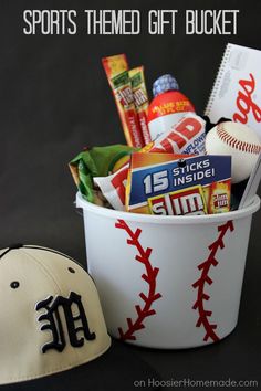 a baseball hat sitting next to a bucket filled with snacks and other sports related items