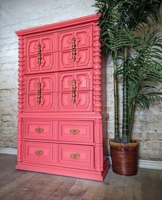 a pink dresser next to a potted plant