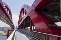 a red bridge that is next to the water