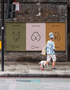 a man walking his dog down the street in front of a building with posters on it