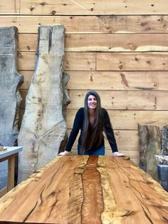 a woman standing on top of a wooden table in front of a wall made of logs