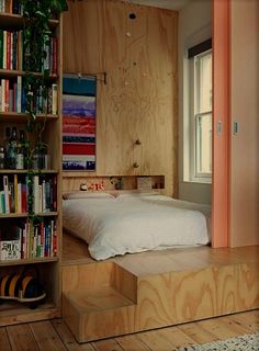 a bed sitting next to a book shelf filled with books