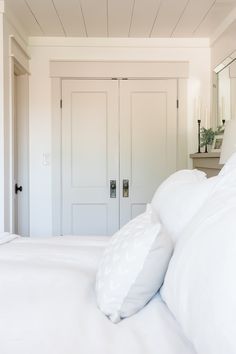 a bed with white sheets and pillows in a room