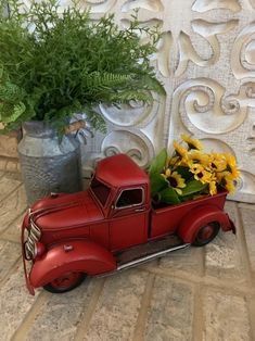 an old red truck with flowers in the back