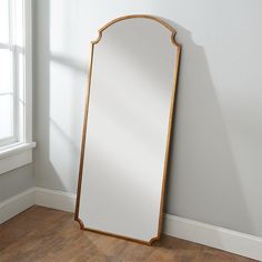 a large mirror sitting on top of a hard wood floor next to a white wall