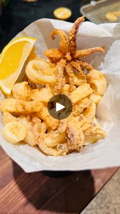 a bowl filled with fried food next to a slice of lemon