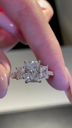 a woman's hand holding a three stone diamond ring