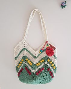 a crocheted bag hanging on the wall next to other items that include beads