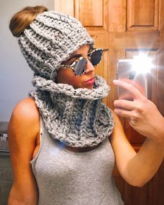 a woman taking a selfie in front of a mirror wearing a knitted hat and scarf