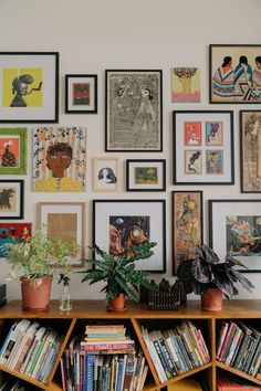 a bookshelf filled with lots of different types of art and pictures on the wall