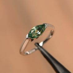 It is a green sapphire ring. The main stone is 5 mm*10 mm marquise cut.weight about 1.34 carats. The basic metal is sterling silver and plated with rhodium/14k white gold/14k rose gold/14k yellow gold You can also go to my shop Home for more elegant rings: https://www.etsy.com/shop/godjewelry?ref=hdr_shop_menu Customization is always welcome and please feel free to contact with me if you have any design ideas! Modern Jewelry With Prong Setting And Marquise Cut, Modern Jewelry With Marquise Cut And Prong Setting, Modern Marquise Cut Jewelry With Prong Setting, Modern Marquise Cut Jewelry With Tension Setting, Modern Marquise Cut Gemstone Jewelry, Modern Silver Marquise Jewelry, Modern Marquise Silver Jewelry, Modern Marquise Cut Promise Ring Jewelry, Elegant Silver Marquise Emerald Ring