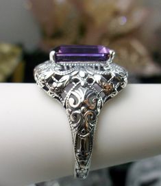 Natural Purple Amethyst Ring Intricate Design#149 Custom Made Inspired by Victorian era designs, I now offer this lovely filigree reproduction in sterling silver. This is a flawless natural purple amethyst is 12mm by 10mm in Length & Width. The ring is 3/4th of an inch North/South on the finger. The inside of the band is etched 925. Notice the intricate and detailed Victorian design of the antique patina silver filigree setting all the way down the band. This is an exquisite rendition of an Vintage Emerald-cut Amethyst Ring For Anniversary, Vintage Emerald Cut Amethyst Ring For Anniversary, Elegant Purple Amethyst Ring With Intricate Design, Purple Hallmarked Art Deco Amethyst Ring, Purple Promise Ring With Intricate Design, Purple Intricate Design Promise Ring, Purple Anniversary Rings With Intricate Design, Art Deco Purple Amethyst Ring, Antique Purple Amethyst Ring With Accent Stones