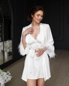 Make your bridal party feel luxurious and pampered with our White Feather Bride Robe Set! Each set includes delicate bridesmaid robes with a matching nightdress for the bride. The bride's nightgown and robe feature stunning feather sleeves for a touch of glamour. This elegant and stylish set makes the perfect bridesmaid gift to show your appreciation for your closest friends on your special day. Let your bridal party relax in style and comfort with this sophisticated White Feather Bride Robe Set Elegant Robe With Feather Trim For Wedding Night, Wedding Satin Robe With Feathers, Feathered Robe For Wedding Night, Elegant Wedding Robe With Feathers, Wedding Satin Dress With Feather Trim, Satin Wedding Dress With Feather Trim, Elegant Satin Dresses For Bachelorette Party, Feathered Dresses For Wedding Night, Elegant Feather Trim Dress For Wedding Night