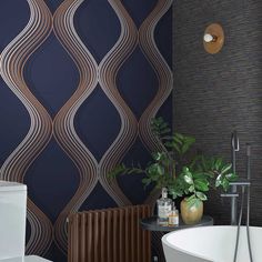 a bath room with a toilet and a tub next to a wallpapered wall