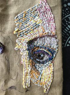 a piece of art made out of different colored beads and threads on top of fabric