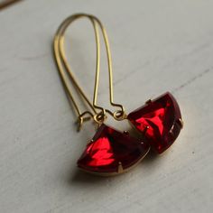 These beautiful fan shaped vintage glass jewels are a beautiful and rich shade of ruby red. The classic fan shape of the stone is reminiscent of Art Deco in its simplicity and strong lines, and the glass has been foiled with gold from behind, so it really catches the light beautifully. The jewel is hung on gold plated ear wires. These earrings are available in two different lengths, which are identical in style and appearance. The longer option is 5cm (two inches) long with the sapphire jewel ha Red Crystal Drop Earrings For Gifts, Nickel Free Red Crystal Earrings For Parties, Ruby Dangle Earrings For Party, Faceted Crystal Earrings For Party, Ruby Teardrop Earrings For Party, Nickel-free Red Earrings For Party, Nickel Free Red Jewelry For Wedding, Nickel-free Red Jewelry For Wedding, Handmade Red Ruby Earrings