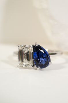 an engagement ring with a blue and white diamond in the center on a white surface