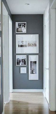 a hallway with pictures on the wall and wooden floors in front of it, along with white framed photos