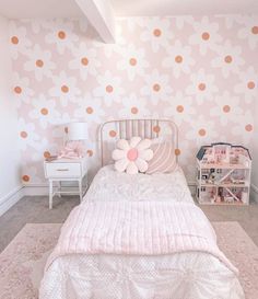 a bedroom decorated in pink and white with polka dots on the wall, bedding and nightstands