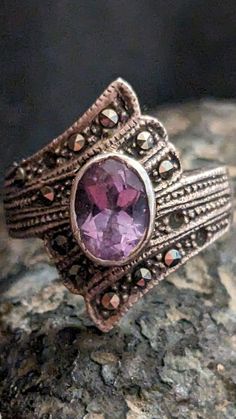 Allow me to introduce you to a piece of jewelry that's truly close to my heart: my vintage silver ring adorned with a mesmerizing amethyst. This exquisite ring encapsulates the timeless beauty and grace of a bygone era. As I gaze at this splendid creation, my eyes are instantly drawn to the captivating amethyst at its center. Its deep, rich purple hue seems to hold the secrets of the ages, and it never fails to leave me in awe. The amethyst is set within a silver frame, a testament to the craftsmanship of a time when artisans paid meticulous attention to detail. The silver band of the ring has a luster that only age can bestow. Its vintage character adds a touch of history and uniqueness to every outfit I pair it with. Wearing this ring, I feel like I'm carrying a piece of the past with me Vintage Amethyst Ring With Accent Stones, Vintage Amethyst Promise Ring, Vintage Silver Amethyst Ring With Accent Stones, Vintage Sterling Silver Jewelry With Center Stone, Vintage Amethyst Ring With Accent Stones For Promise, Vintage Amethyst Ring With Center Stone For Promise, Vintage Silver Birthstone Ring With Center Stone, Vintage Birthstone Ring With Accent Stones As Gift, Vintage Amethyst Ring With Accent Stones For Collectors