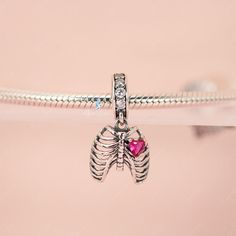 This is charm only, bracelet is sold separately. Experience true love with this exquisite pendant charm featuring a silver rib cage adorned with a stunning pink heart stone. Made of high-quality 925 sterling silver, its polished finish adds a brilliant shine and is accented with a platinum plating. Add this beautiful love oath of rib dangle pendant charm to your bracelet or gift it to your special someone. Materials: 925 sterling silver, cubic zirconiaFinish: platinum plateDimensions: 0.76 x 0.4 Silver Heart Charm In Metal, Silver Metal Heart Charm, Silver Sterling Charm Necklace With Removable Charms, Dainty Silver Charms With Removable Features, Dainty Silver Charms With Removable Feature, Silver Sterling Birthstone Charms, Sterling Silver Charms With Birthstone, Sterling Silver Dangle Jewelry With Heart Charm, Pink Sterling Silver Dangle Charms