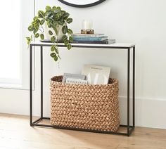 a small table with a basket underneath it and a clock on the wall behind it