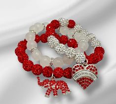 In this COLEction, we proudly present our designs crafted with utmost respect for these beautiful ladies. Each exquisite piece has been hand strung, radiating an enchanting blend of shiny red and white colors, reflecting the timeless crimson and cream symbolism. The 10mm beads, whether made of glass, matte or rhinestone coated clay, exude an air of elegance that perfectly complements these sophisticated ladies. Adorned with dazzling charms, each item becomes a testament to their refined taste an Spiritual Red Stretch Bracelet Gift, Spiritual Red Stretch Bracelet As Gift, Adjustable Red Hand-strung Crystal Bracelet, Red Adjustable Crystal Bracelet For Valentine's Day, Adjustable Red Stretch Bracelet For Valentine's Day, Adjustable Red Crystal Bracelet For Valentine's Day, Elegant Red Bracelets For Friendship, Elegant Red Friendship Bracelets, Elegant Red Hand-strung Stretch Bracelet