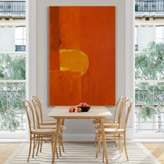 a painting on the wall above a table with four chairs and a bowl of fruit