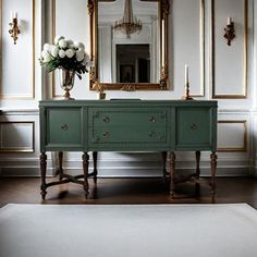 a green dresser sitting in front of a mirror on top of a wooden floor next to a white rug