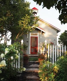 a small house with a red door and white picket fence