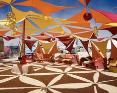 an outdoor area with many colorful umbrellas on the ground and tables set up under them