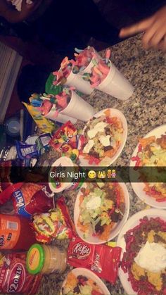 a table topped with plates of food next to bottles of soda and condiments