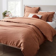 a bed with an orange comforter and pillows