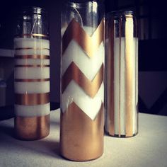 three gold and white vases sitting on top of a table