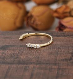 a gold ring with three stones on it sitting on top of a wooden table next to some fruit