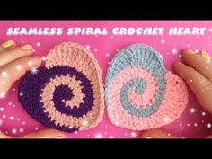 two crocheted hearts sitting next to each other on top of a pink surface