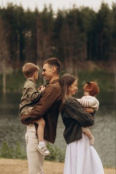 a man, woman and child standing on the beach with trees in the back ground