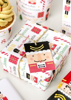 a wrapped present box sitting on top of a table next to cupcakes and cookies